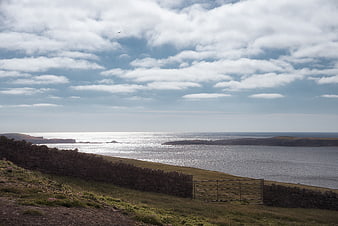 Coastal landscape with stone wall and cloudy sky
