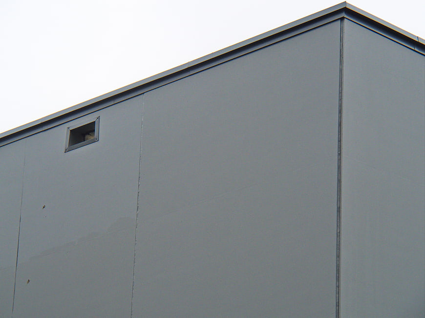 Minimalist gray industrial building facade with small window