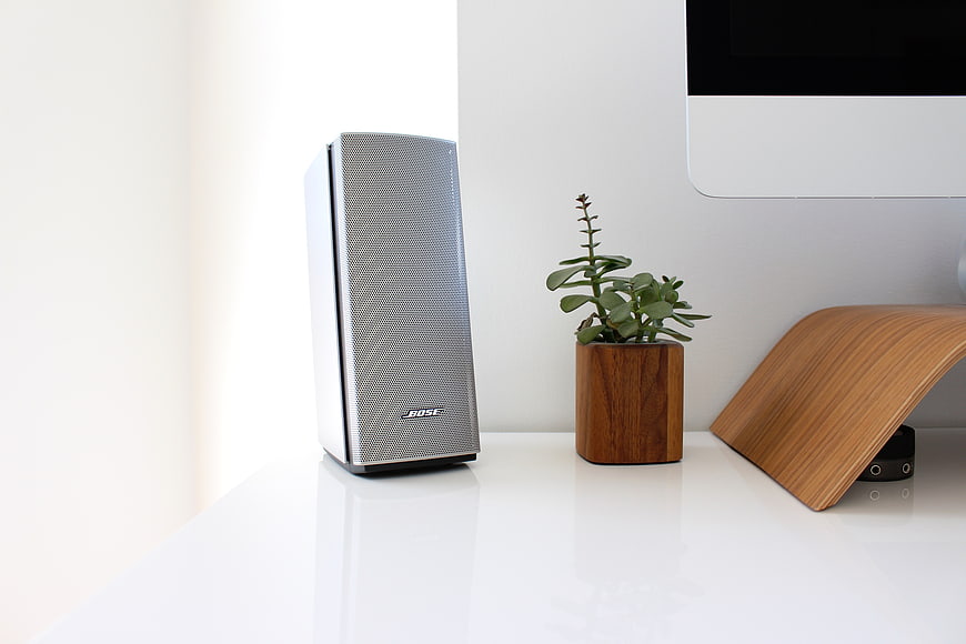 Modern Bose speaker on white desk with plant and computer