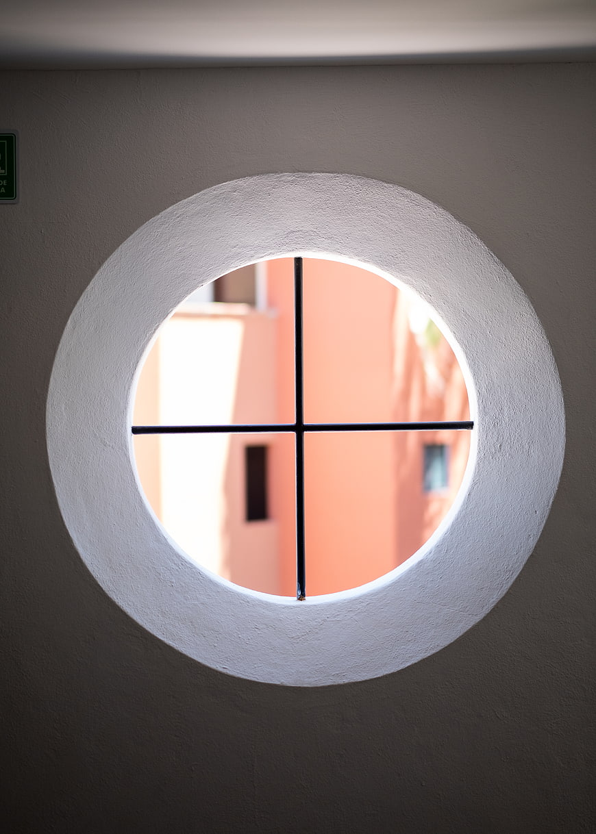 Round window with cross frame looking at peach building