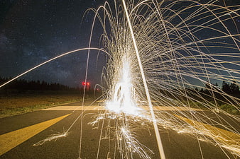 Steel wool sparks long exposure on road under starry night sky