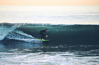 Surfer Riding a Large Ocean Wave at Sunset