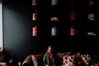 Woman sitting on leather sofa in dark room with vintage tins