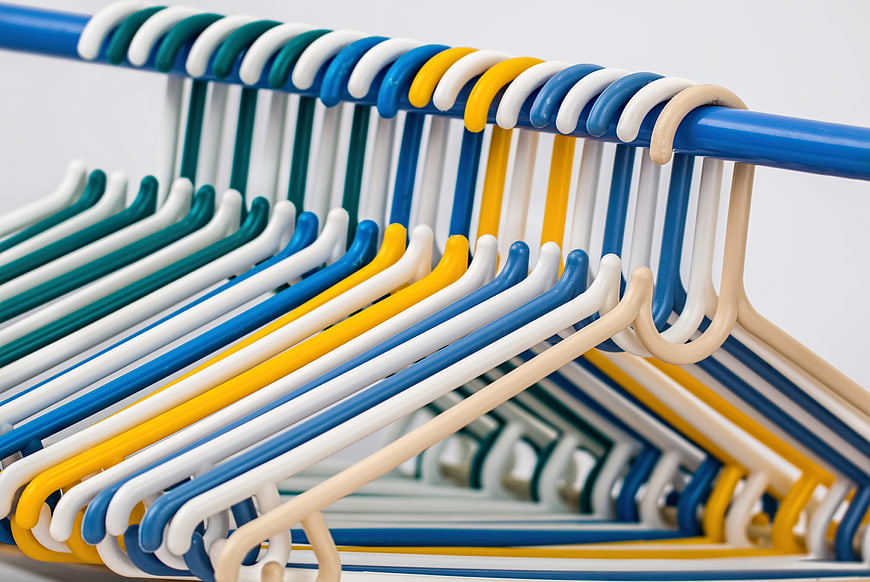 Colorful plastic clothes hangers on a blue rack
