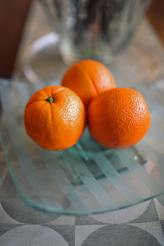 Three fresh oranges on a glass plate