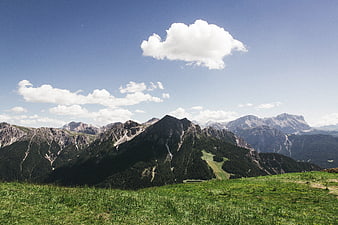 Alpine mountain landscape with green meadow and blue sky