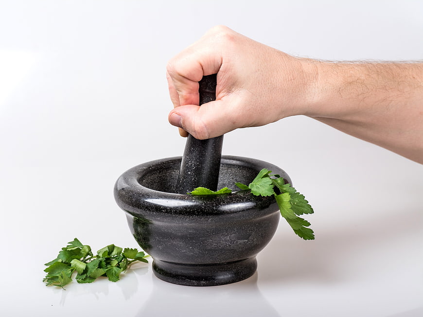 Hand Crushing Fresh Parsley in Black Stone Mortar