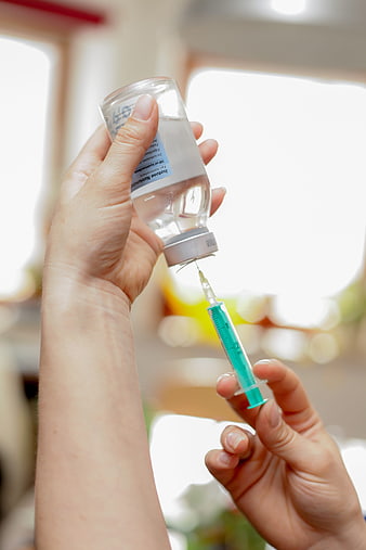 Close-up of hands drawing saline solution into a syringe