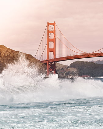 Golden Gate Bridge with crashing waves and pink sky