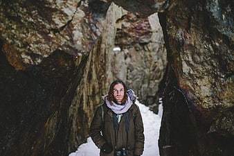 Man with Camera Standing in Snowy Rock Tunnel