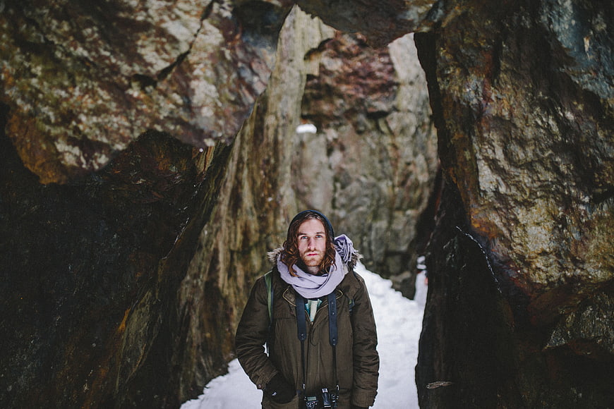 Man with Camera Standing in Snowy Rock Tunnel