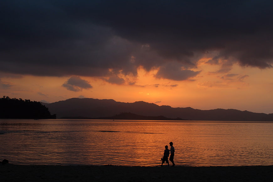Silhouette of Two People Walking on Beach at Sunset