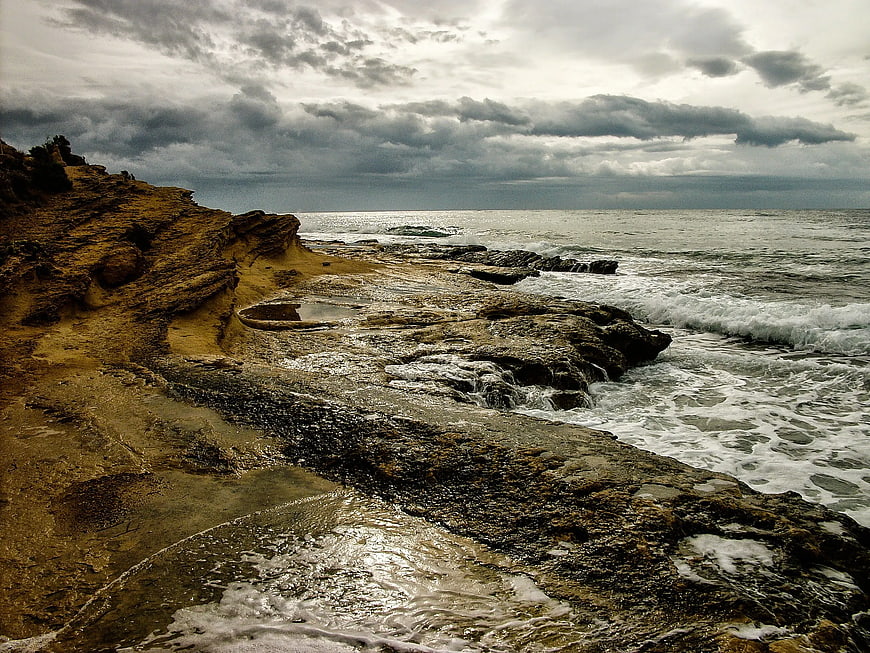 Dramatic Rocky Coastline with Crashing Waves and Cloudy Sky
