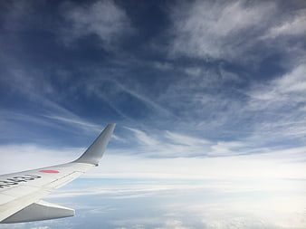 Airplane wing view over clouds and blue sky