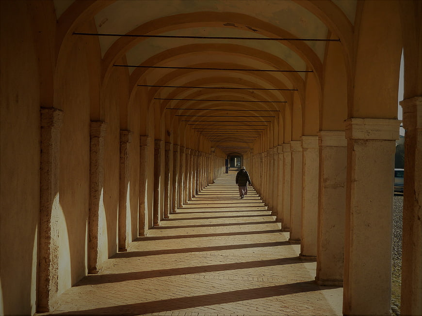 Solitary figure walking through a long arched colonnade