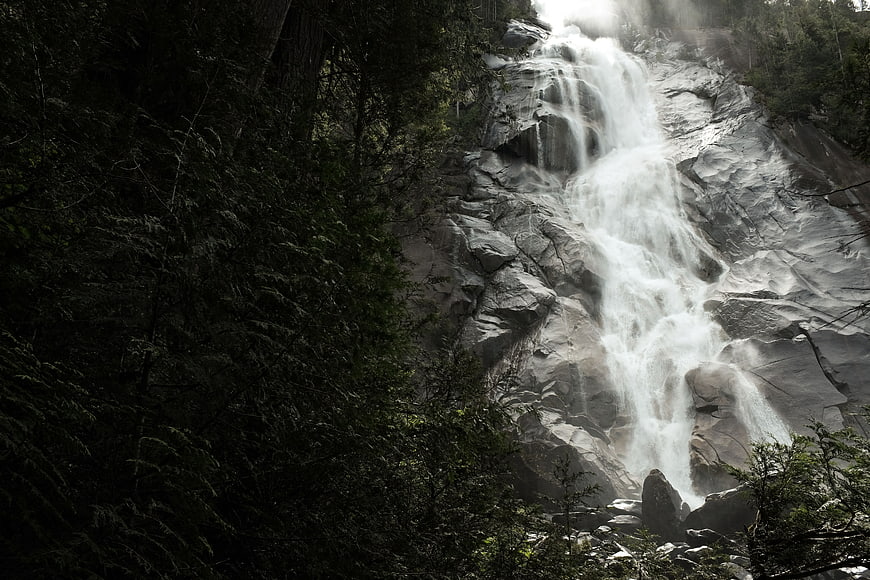 Majestic waterfall cascading down rocky cliff in forest