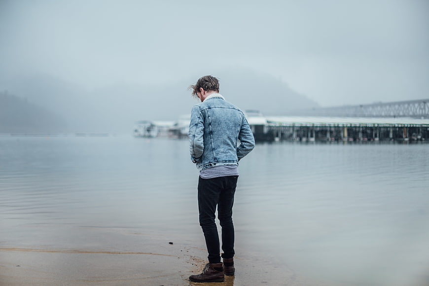Man in Denim Jacket Standing by Foggy Water