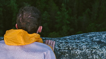Man in Yellow Hoodie Looking at Forest from Cliff