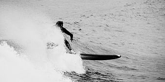 Black and white surfer riding a wave with spray