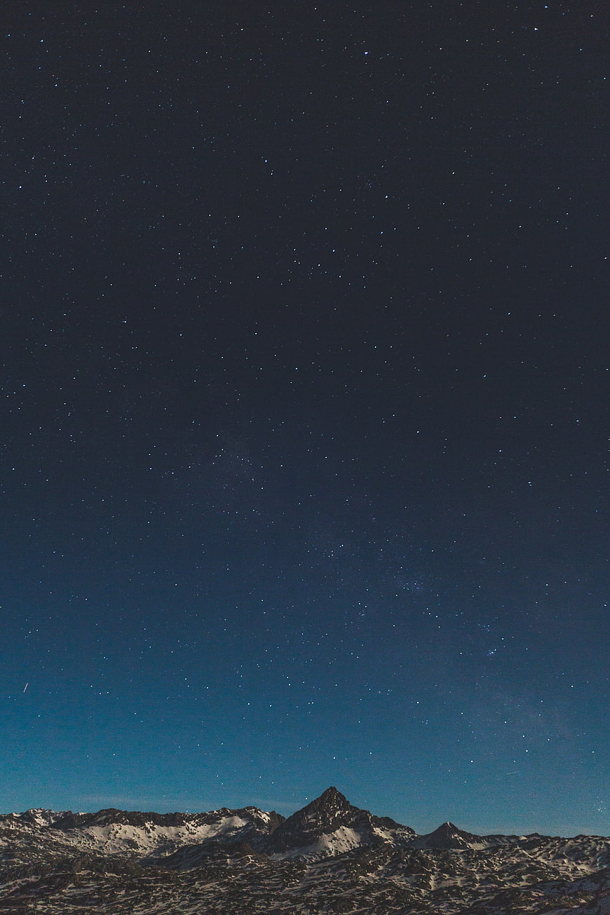 Starry Night Sky Over Snowy Mountain Peaks