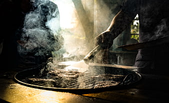 Close-up of meat grilling on charcoal barbecue with smoke