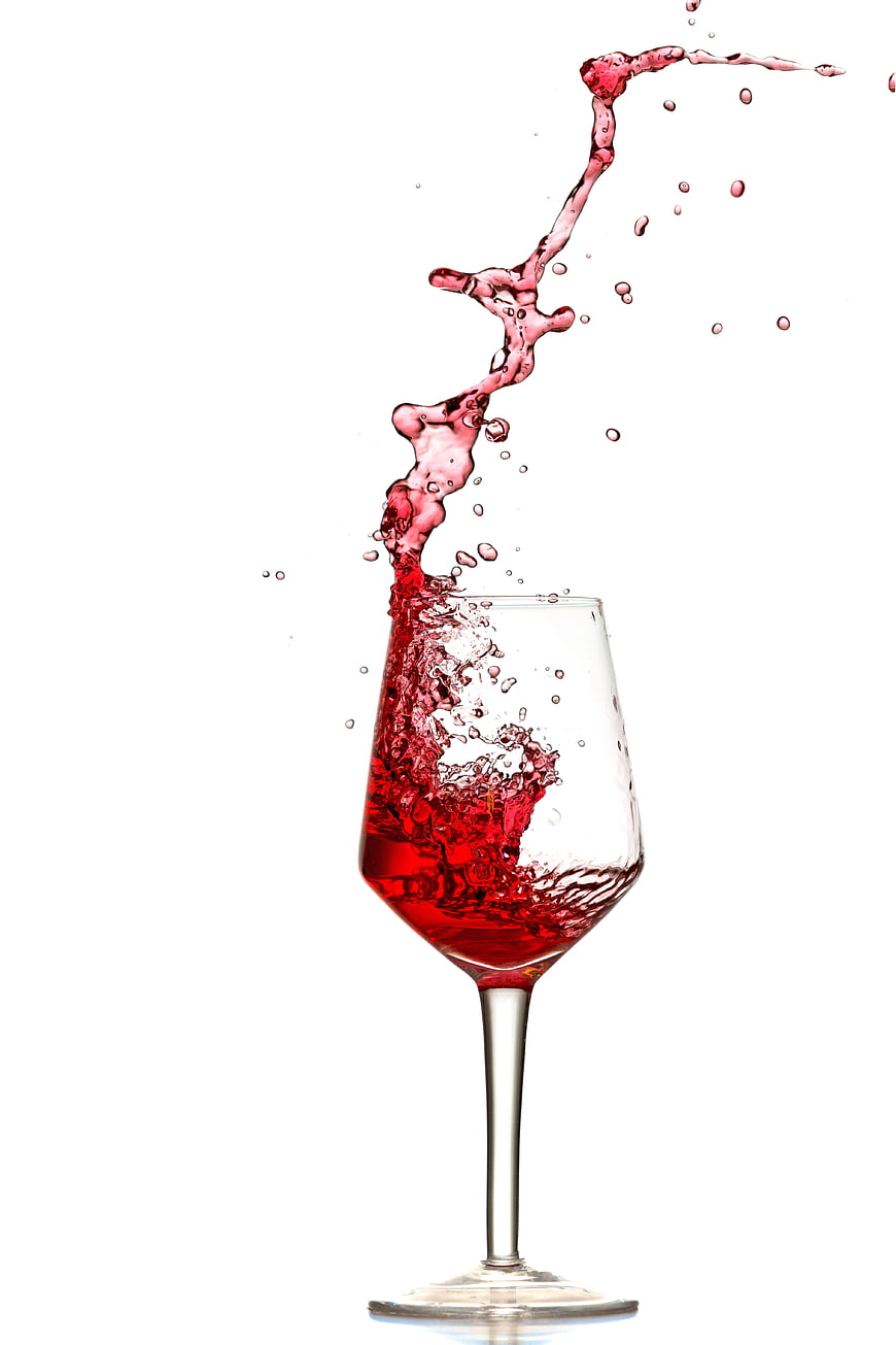 Red wine splash in glass on white background
