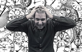 Stressed man holding head against clock background