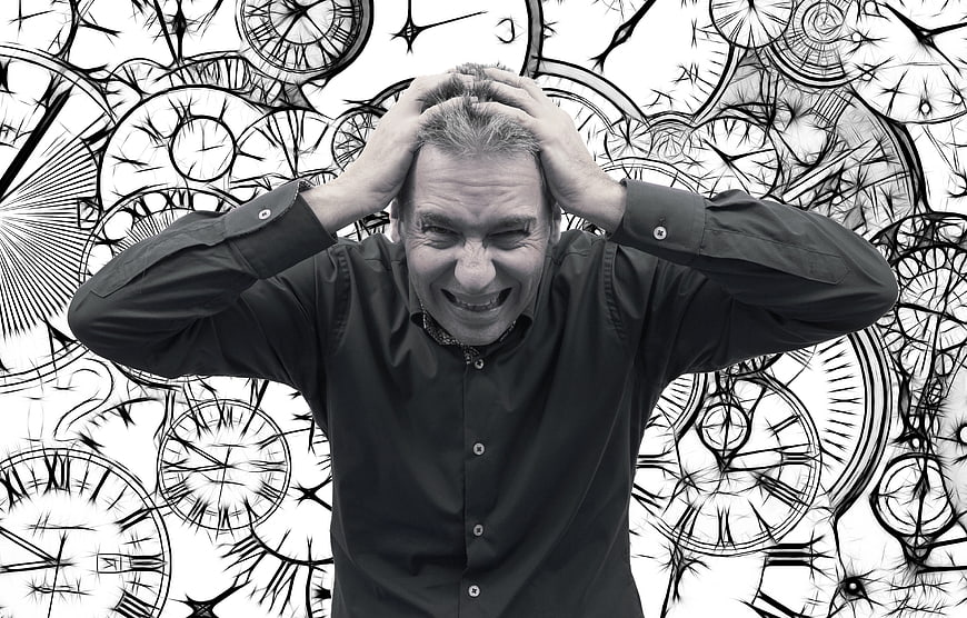 Stressed man holding head against clock background