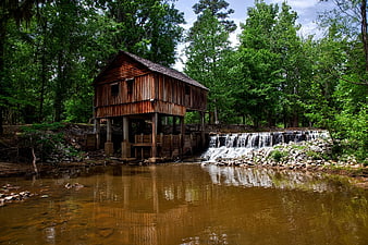 Historic wooden grist mill on a river with waterfall