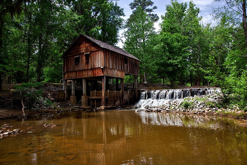 Historic wooden grist mill on a river with waterfall