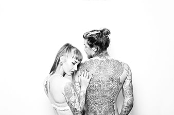Black and white portrait of a tattooed couple embracing in a studio