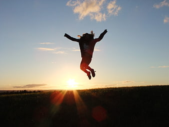 Silhouette of Girl Jumping in Field at Sunset