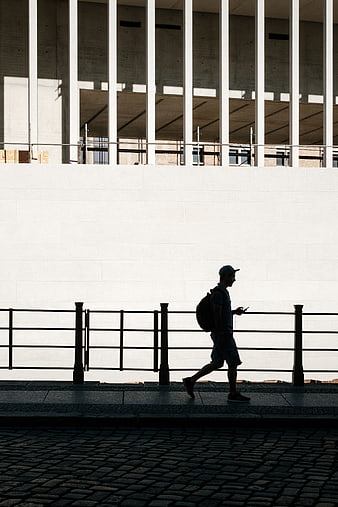 Silhouette of Man Walking Past Modern Concrete Architecture