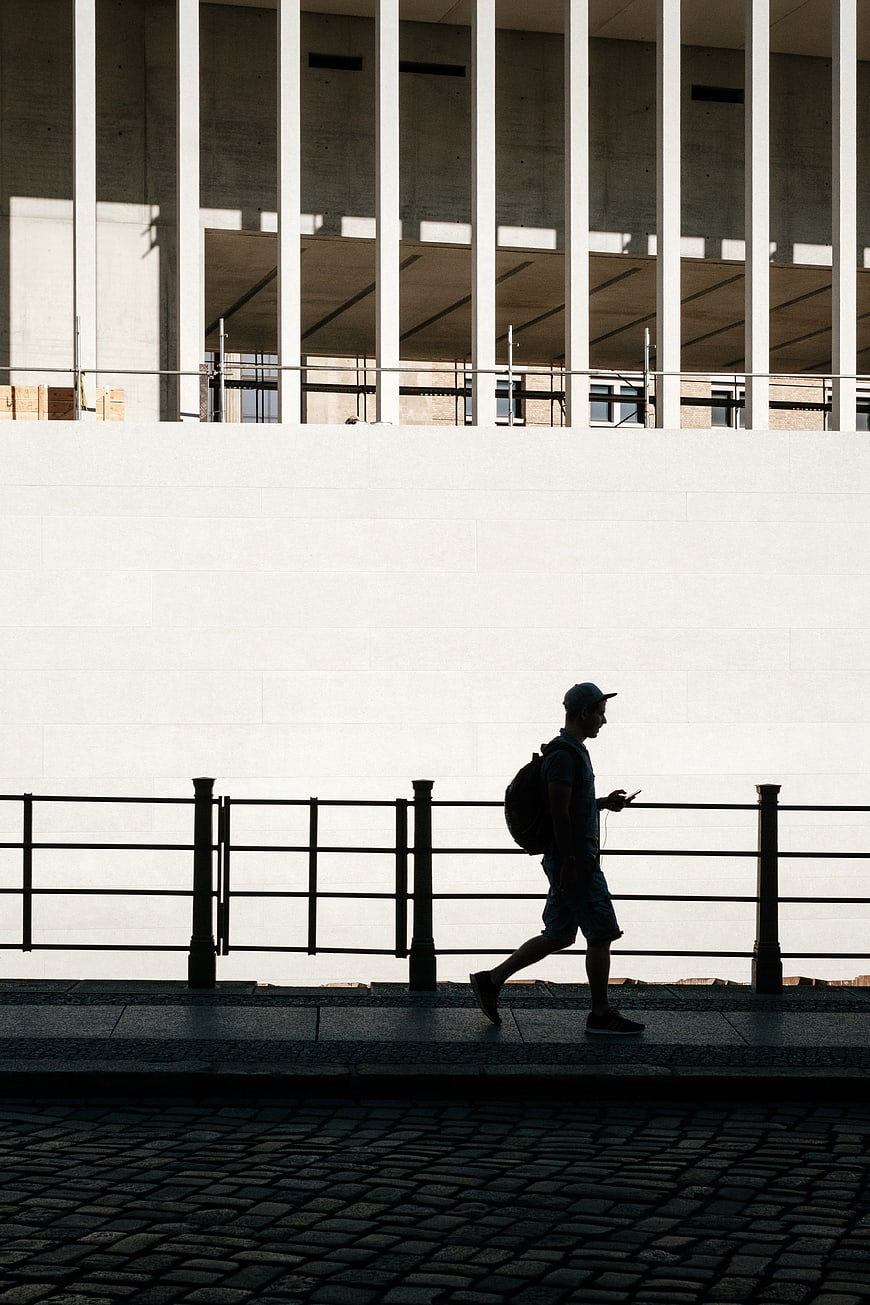 Silhouette of Man Walking Past Modern Concrete Architecture