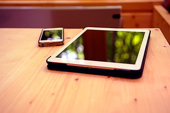 Tablet and Smartphone on Wooden Table with Blurred Background