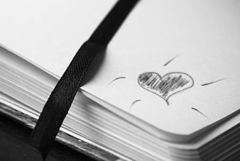 Hand-drawn heart sketch on open notebook page with black ribbon