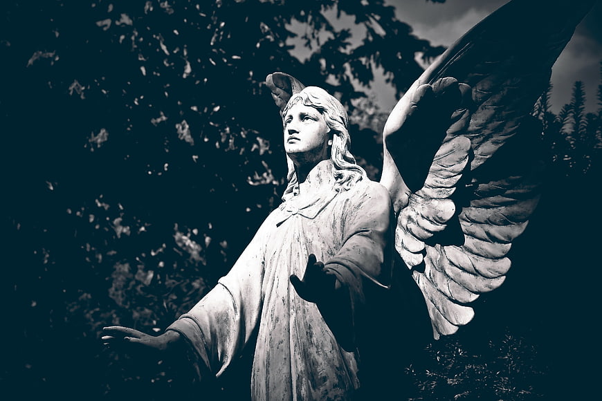 Dramatic Low Angle View of Weathered Stone Angel Statue in Cemetery