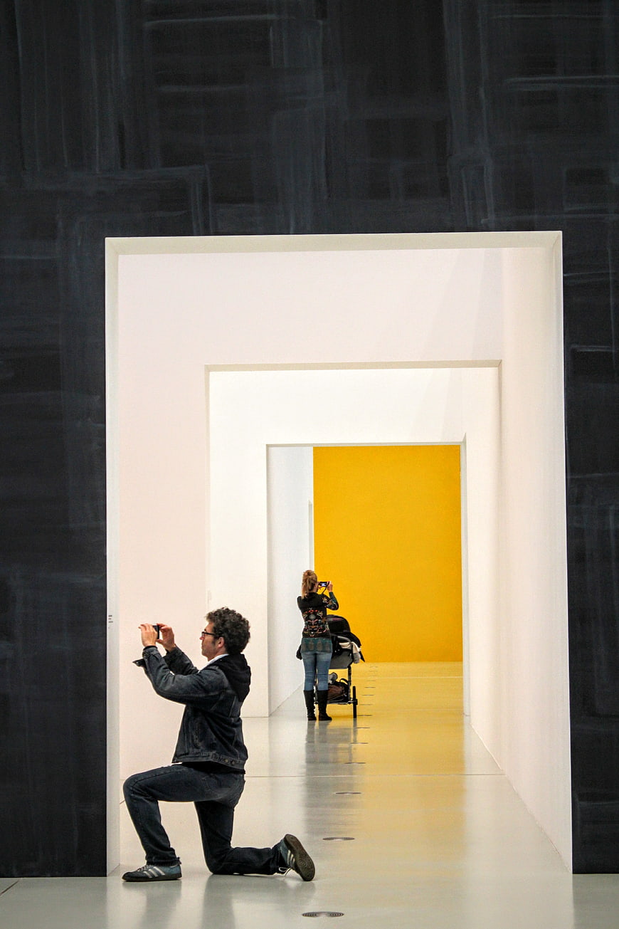Man photographing woman in modern art gallery tunnel