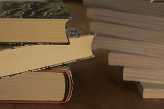 Close-up of stacked vintage hardcover books on a wooden table