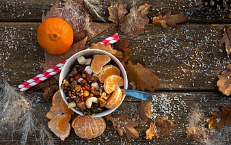 Autumn breakfast bowl with granola, clementines, and nuts on rustic wood