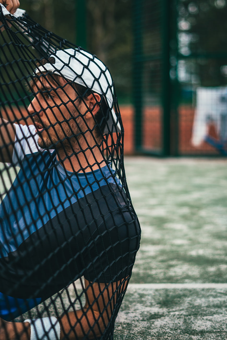 Male Tennis Player Holding Net on Court
