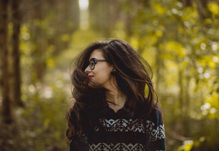 Woman with glasses and patterned sweater in autumn forest