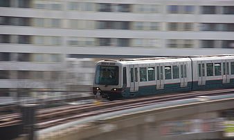 Fast-moving silver and teal commuter train on urban tracks