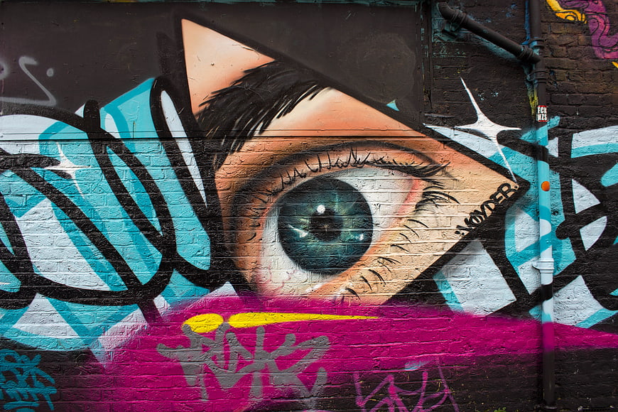 Vibrant graffiti mural of a realistic eye on brick wall