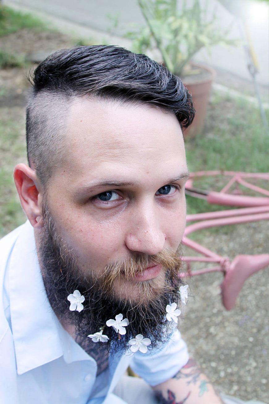 Portrait of Man with Flowers in Beard Outdoors