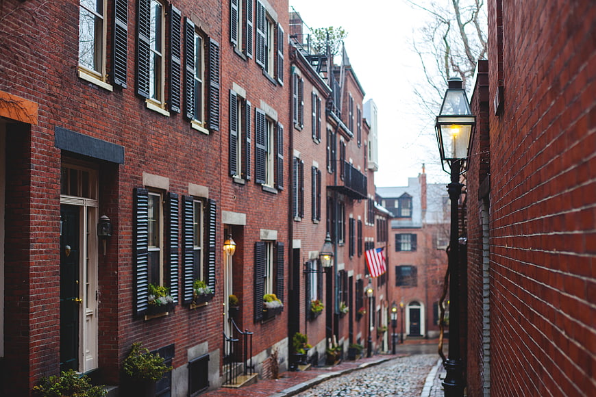 Historic cobblestone alley with red brick buildings and black shutters