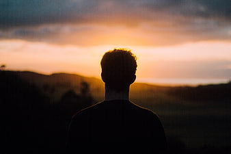 Silhouette of Man Watching Sunset Over Rolling Hills
