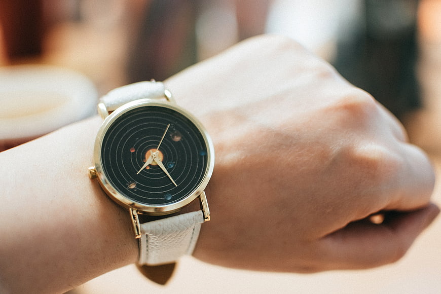 Close-up of wristwatch with solar system design on hand