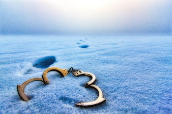 Open handcuffs on snow with footprints leading into the distance
