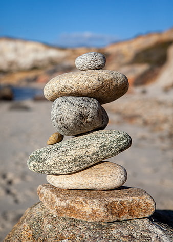 Stacked Beach Stones on Sand with Blurred Coastal Background